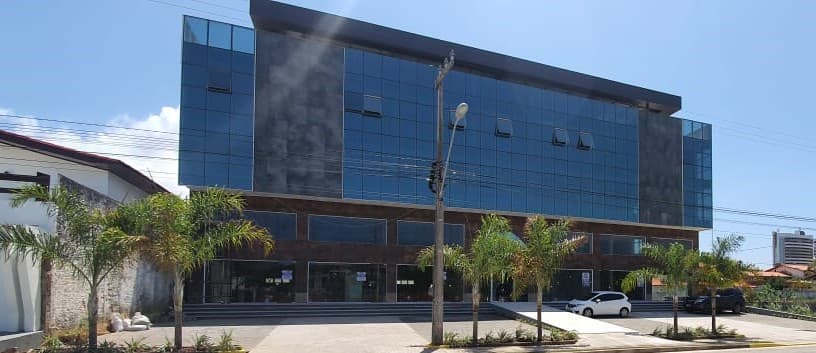 Fachada de vidro da Galeria A, na Av. dos Sambaquis, com o pátio de vagas na frente